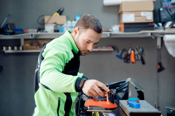 Man worker in service workshop, preparation sliding surface of cross-country ski. Wax is applied with hot iron