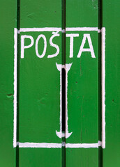 A slot in a green wooden door for receiving correspondence stylized as a mailbox with a white rectangle and the word "Post" from various Cyrillic languages