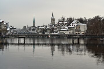 Zurich, Switzerland, 12 18 2022 Panoramic view of old town Zurich captured in winter. Limmat river is on foreground. Churches St. Peter and Frauenmuenster and other buildings mirror in water.