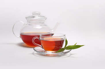 Tea cup and glass teapot on light background.