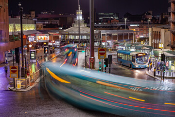 Busy bus station at night, long exposure light streaks from traffic