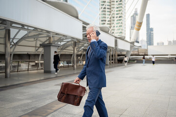 Asian senior mature middle aged businessman using smartphone in modern city
