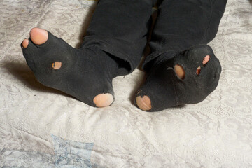 View of torn worn socks on a lying man. The concept of poverty.