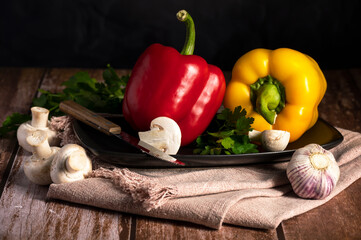 Mushrooms, red and yellow peppers lie on the table in the kitchen 
