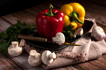 Mushrooms, red and yellow peppers lie on the table in the kitchen 
