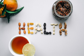 The word Health is lined with nuts and dried fruits. In addition, lemon tea, tangerines and dried fruit paste are in the photo. Healthy lifestyle, sports.