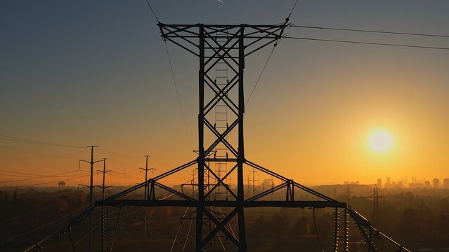 Power tower with electricity. Energy and high voltage electricity pylon at Sunset or golden hour. Power demand and outage blackout concept due EV or electrical vehicle increase. Grid infrastructure.