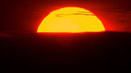 African sunset time lapse with big sun disk and backlit clouds. Cinematic and epic hot summer sunset with big red and orange sun circle.