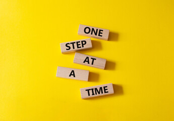 One step at a time symbol. Concept words One step at a time on wooden blocks. Beautiful yellow...