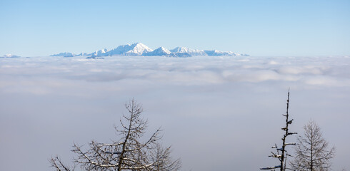 Winter mountains covered with snow landscape over clouds