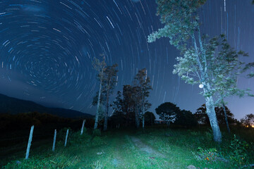 Star trails. Movement of stars in the sky towards the south pole. Country road in the mountain at...