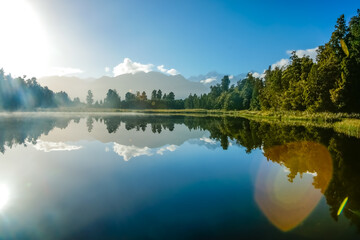 Naklejka premium Reflections in Lake Mathieson surrounded by natural bush and forest and Southern Alps mountain range