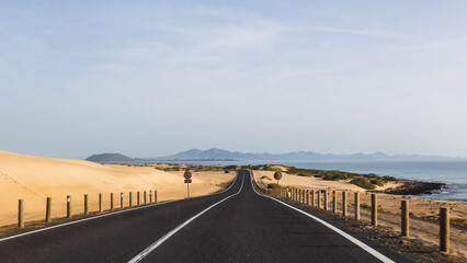 Coastal asphalt road crossing Corralejo Dunes National Park on Fuerteventura island, Canary Islands, Spain