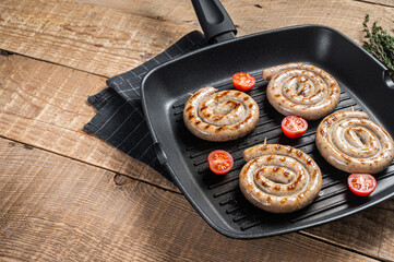 Fried on a grill pan spiral meat sausages with spices. Wooden background. Top view. Copy space