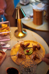 Wooden round plate with delicious snacks on cafe table