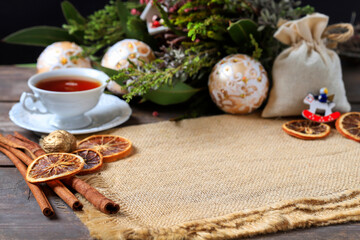 Obraz na płótnie Canvas A cup of hot tea among Christmas decorations. Cozy atmosphere.