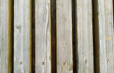 An ancient wooden background with peeling paint. The boards are grey. The boards are arranged in parallel. Texture. Background.