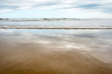 Fototapeta na wymiar Sand and water, empty beach, reflection of the sea and sky