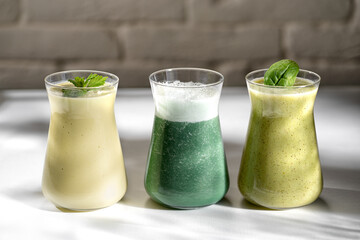 Freshly blended fruit smoothies of various colors and tastes in glass jars. Yellow green.