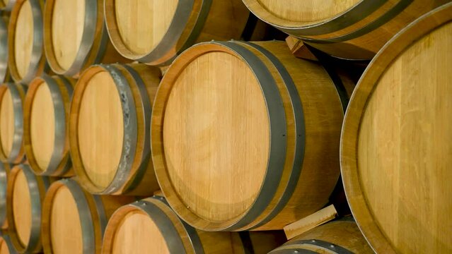 A Wine Cellar. Storage Room for Wine in Bottles and Barrels. Old wine in a dark underground vault. Wooden oak wine barrels. Bottles on wooden shelves.
