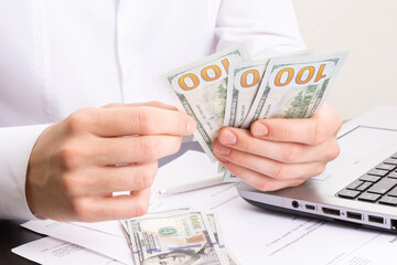 caucasian hands counting dollar banknotes on white wooden surface