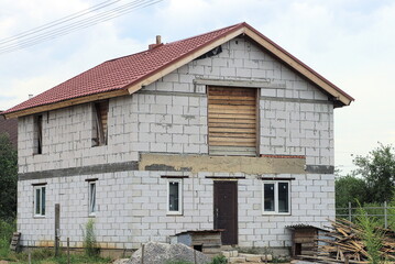 one private house of white bricks with windows under a brown tiled roof on the street in green grass