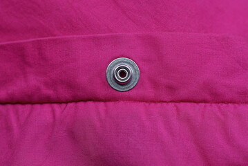 one gray metal button rivet made of red fabric on clothes