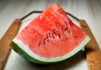 quarter cut watermelon on tray and wooden table