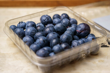 Fresh blueberries in transparent plastic container for sale
