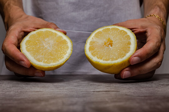 Male hands cutting a ripe yellow lemon with a knife on a slate table. Front view.