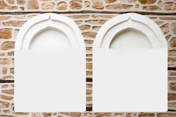 This shows framework of two windows. The material is a medieval reproduction. The arches show against an old rock stone wall. The window frames are clear white solid ready for your text or image.