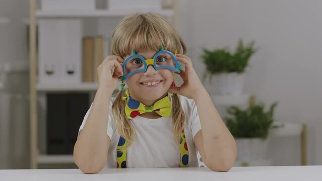 Funny girl of 7 years dressed in clown eye glasses, butterfly and suspenders.