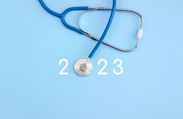 Stethoscope and numbers 2023 on blue background. The concept of health care in the New Year. Blank...