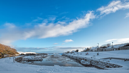 Brora harbour with winter snow and blue sky