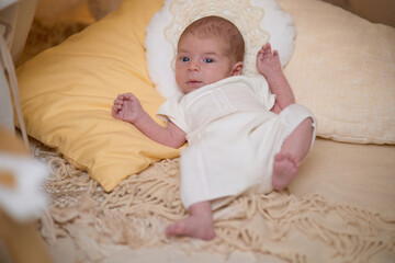 Newborn baby for the first time at home, lying in a blanket on the bed, smiling, yawning, pulling pens, falling asleep, baby's morning, baby products concept