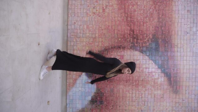 vertical blonde woman dancing in front of murals with two lips kissing each other, love freedom passion concept