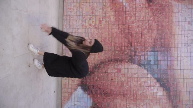 vertical young blonde woman dancing in black dress with two lips kissing in background wall murales, sexy sexual freedom concept
