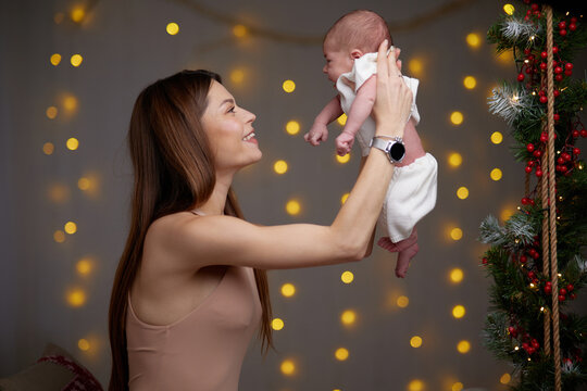 Pretty woman holding a newborn baby in her arms. A woman rejoices, hugs and kisses a child, talks and rejoices her baby, happy smiles on the face of mother and baby.
