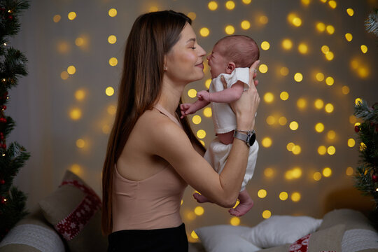 Pretty woman holding a newborn baby in her arms. A woman rejoices, hugs and kisses a child, talks and rejoices her baby, happy smiles on the face of mother and baby.
