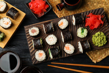 Obraz na płótnie Canvas Tasty sushi rolls served on black wooden table, flat lay