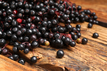Black elderberries (Sambucus) on wooden table, closeup