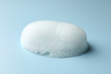 Drop of fluffy soap foam on light blue background