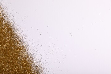 Shiny golden glitter on white background, top view