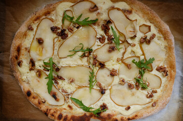 homemade sweet pizza with cheese, pear, walnut and arugula leaves