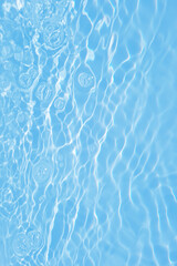 Fototapeta na wymiar Defocus blurred transparent blue colored clear calm water surface texture with splashes and bubbles. Trendy abstract nature background. Water waves in sunlight with caustics. Blue water shinning 