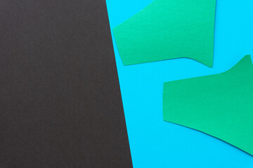 two green paper shapes on smooth brown and blue paper background
