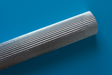 corrugated silver tube on smooth blue paper