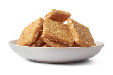 coconut biscuits, textured crispy square shaped homemade cookies on a white plate isolated
