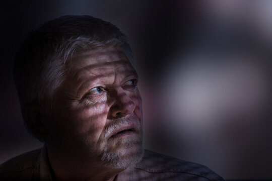 Portrait of an elderly man, he looks longingly into the light, the shadow of a lattice can be seen on his face