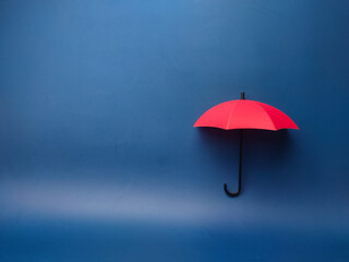  A red umbrella on a blue background with copy space., planning, saving families, preventing risks...